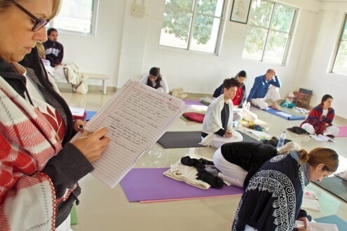 Group of YTT students taking notes in yoga during a theory class Students taking notes in during their YTT theory session