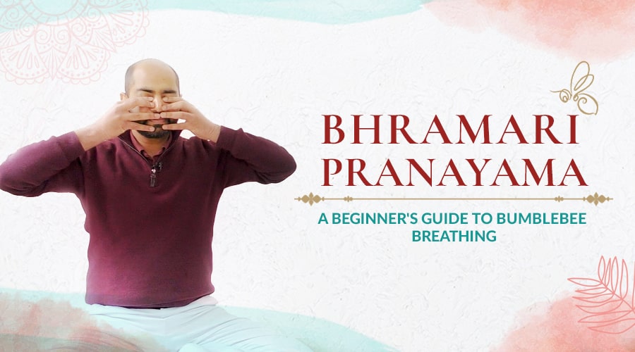 A young man sits on a yoga mat in a seated position practicing easy Bhramari Pranayama.