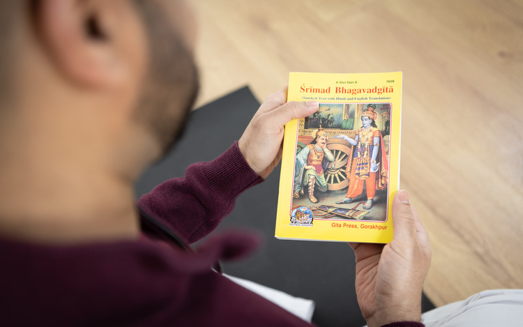 Over the shoulder view of someone holding sacred Bhagavad Gita Self-reflection through reading Bhagavad Gita