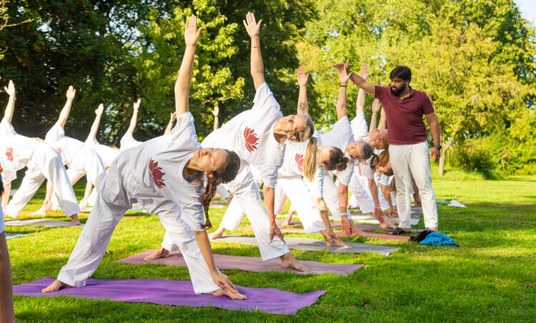 An Indian yoga instructor teaches a class of students Hatha Yoga poses outside An Indian yoga instructor teaches a class of students Hatha Yoga poses outside