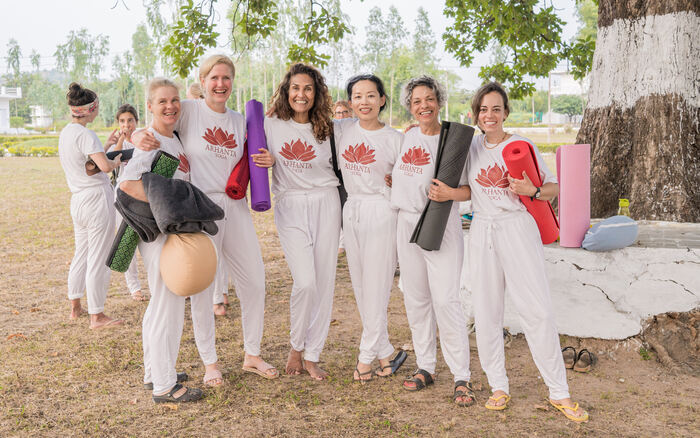Yoga students posing with smiling faces, unwinding after an intense session YTT students’ group posing together after an outdoor practice session