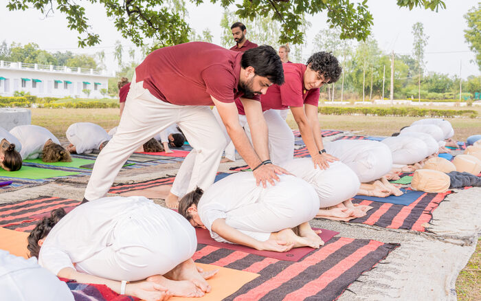 Yoga teacher demonstrates adjustments at a yoga teacher training in India
