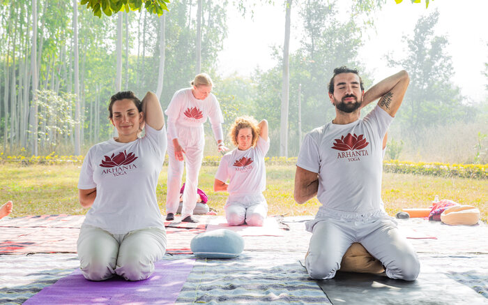 Students practicing Gomukhasana in a kneeling position 