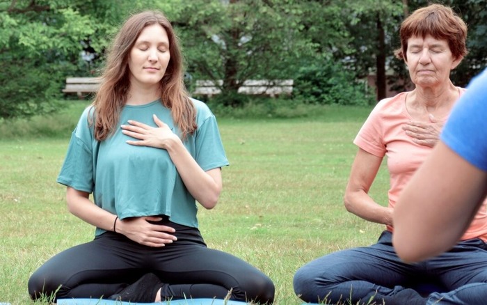 Group of yoga practitioners meditate outside to balance their doshas