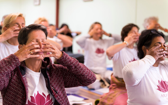 Instructor Dr. Ram Jain guiding seated student in yoga adjustment