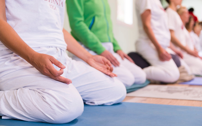 Yoga students sit on a yoga cushion during meditation Yoga students sit on a yoga cushion during meditation
