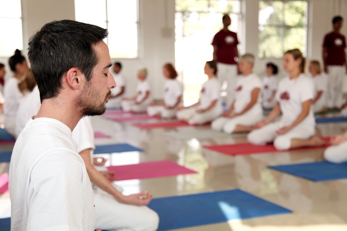 Group of yoga practitioners practice pranayama breathing techniques for stress and anxiety relief