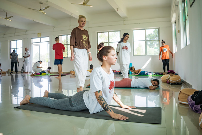 Yoga teacher fixes a student’s alignment in Cobra Pose Yoga teacher fixes a student’s alignment in Cobra Pose