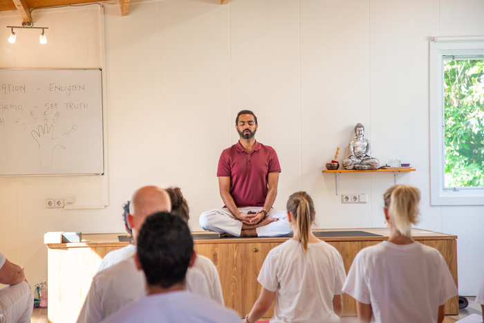 Yoga teacher meditates in front of a class of students Yoga teacher meditates in front of a class of students