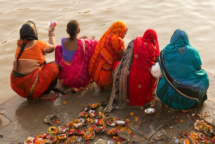 Five women in traditional Indian clothing pray beside the Ganga in Varanasi