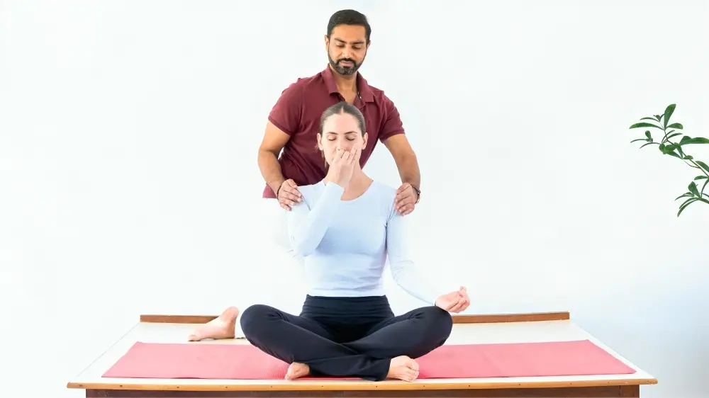 Trainer Dr. Ram assisting seated Yin Yoga student Dr. Ram Jain assisting seated Yin Yoga student on mat
