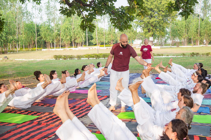 Yoga teacher adjusts students’ yoga poses during an outdoor yoga class Yoga teacher adjusts students’ yoga poses during an outdoor yoga class