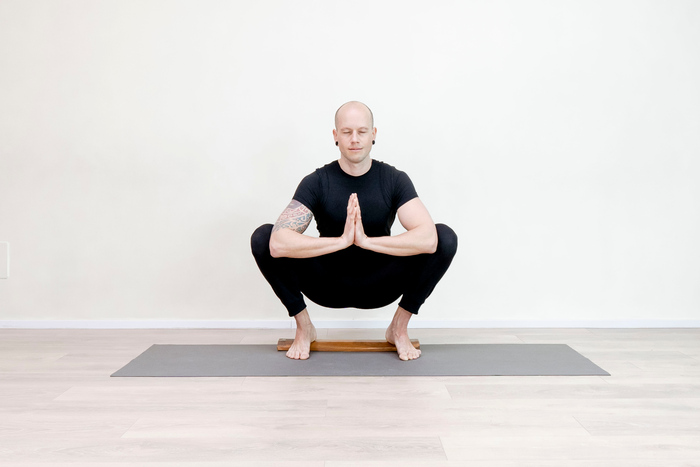 Male yoga practitioner in a yoga squat (Malasana) Male yoga practitioner in a yoga squat (Malasana)