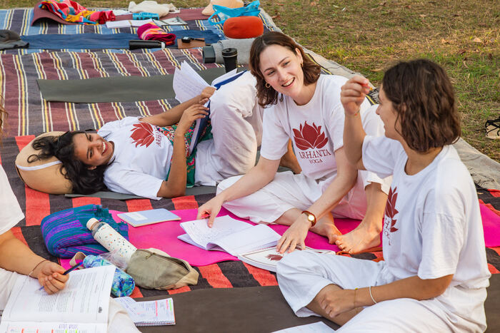 Students study together outside on a yoga teacher training in India