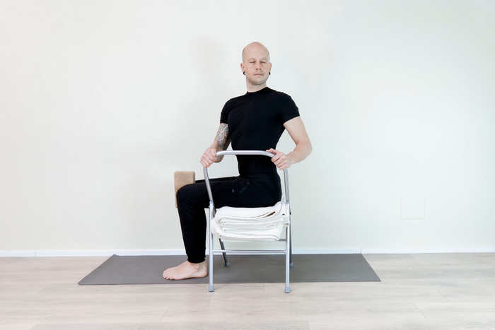 A man demonstrates chair yoga for men over 40 A man demonstrates chair yoga for men over 40
