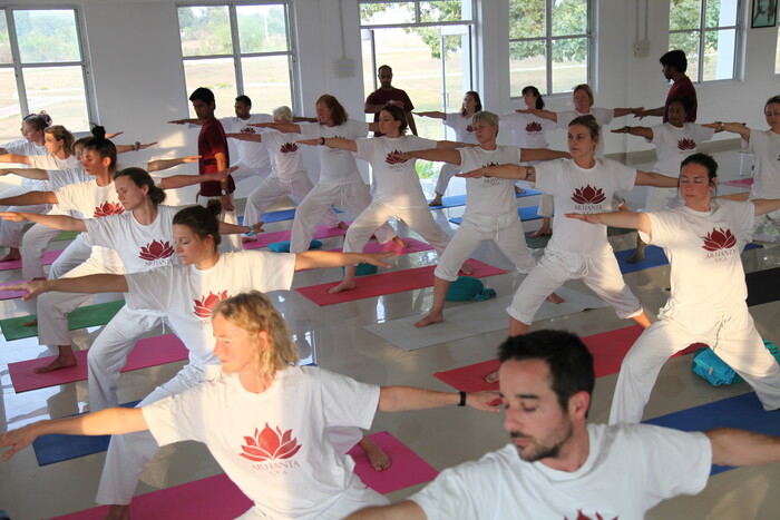 Students practicing warrior pose at yoga ashram Students practicing warrior pose at yoga ashram