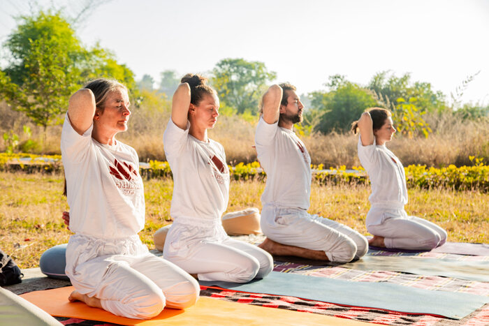 Students practicing Vajrasana in an outdoor setting Students practicing Vajrasana in an outdoor setting