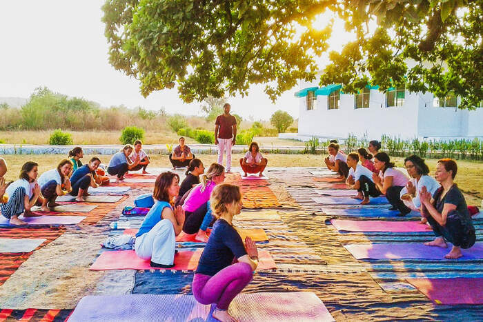 Teacher guiding students in Malasana Teacher guiding students in Malasana
