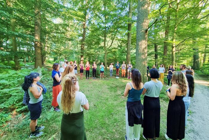 Group of yoga students standing in a circle surrounded by a lot of greeneries