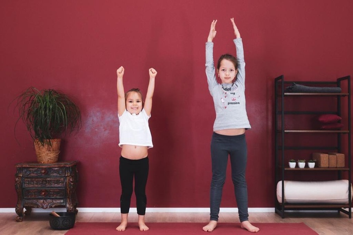 Two young kids standing barefoot keeping arms raised in Tadasana Two young kids standing barefoot keeping arms raised in Tadasana
