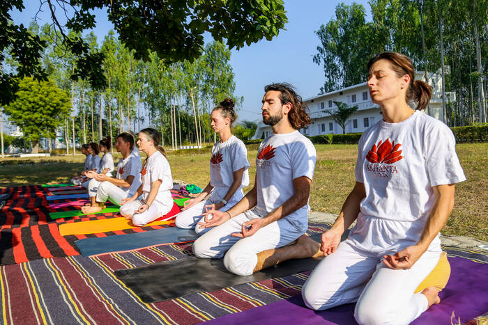 Pratyahara Practice for Inner Awareness Yoga students practicing meditation outdoors to reduce sensory distraction