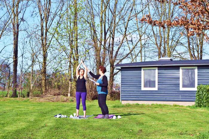 Two students practicing Urdhva Hastasana in an outdoor setup